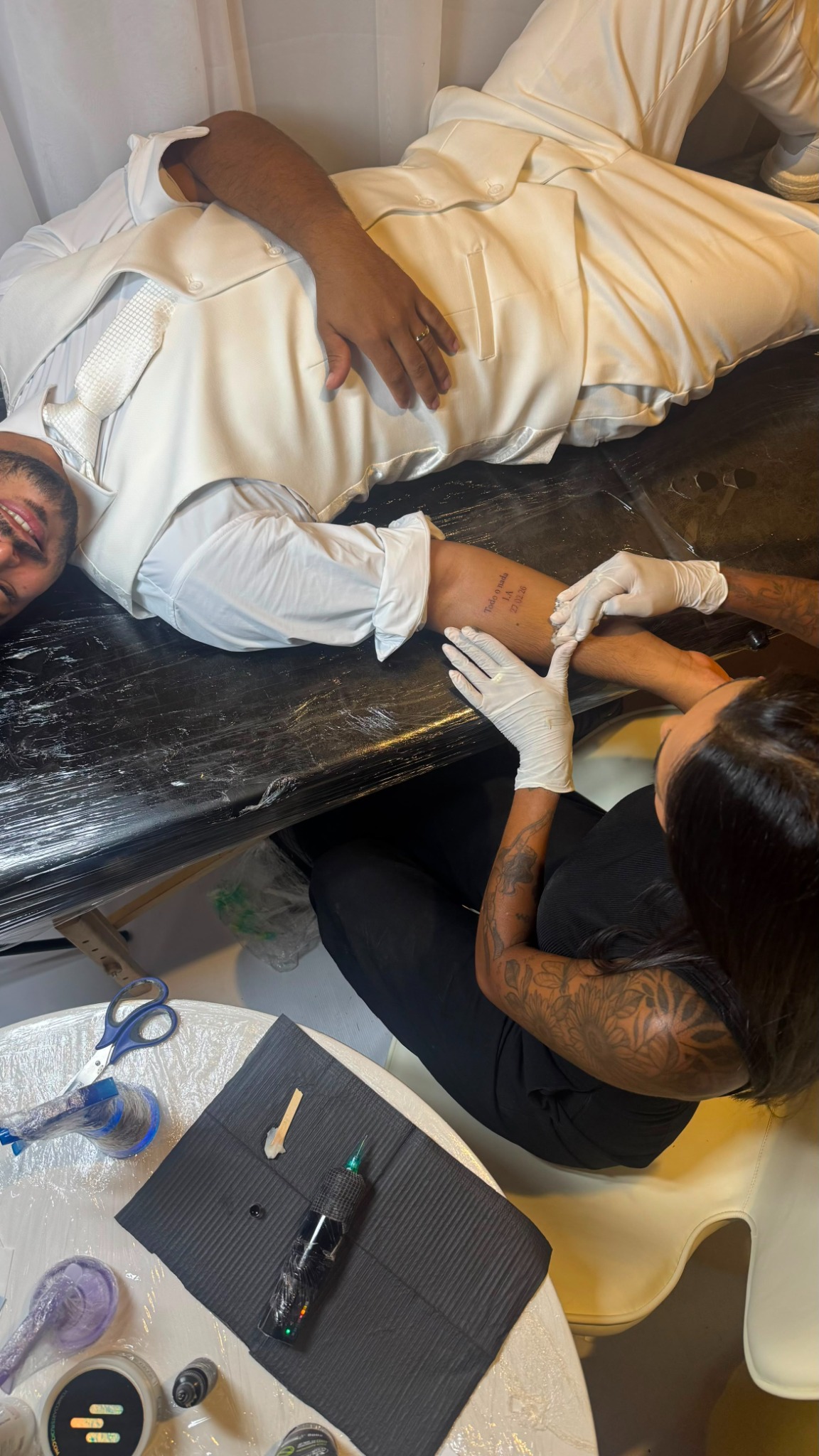 Convidado vestido para casamento recebendo uma tatuagem fine line